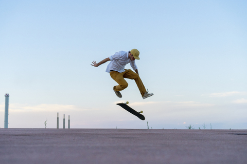 Young man doing a skateboard trick on a lane at dusk stock photo