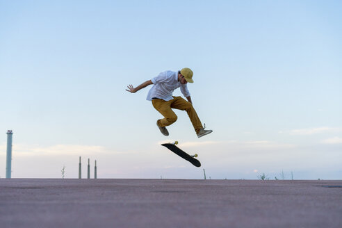 Junger Mann macht einen Skateboardtrick auf einer Fahrbahn in der Abenddämmerung - AFVF01516