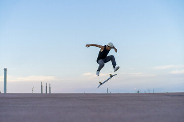 Young man doing a skateboard trick on a lane at dusk - AFVF01517