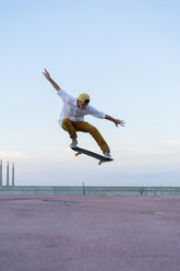 Junger Mann macht einen Skateboardtrick auf einer Fahrbahn in der Abenddämmerung - AFVF01519