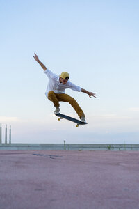 Junger Mann macht einen Skateboardtrick auf einer Fahrbahn in der Abenddämmerung - AFVF01519