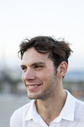 Porträt eines lächelnden jungen Mannes mit zerzaustem Haar im Freien - AFVF01521