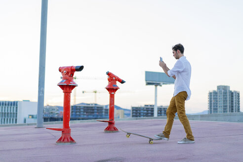 Junger Mann mit Skateboard und Mobiltelefon - AFVF01522