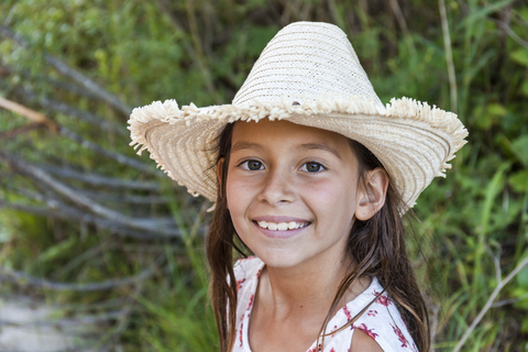 Porträt eines lächelnden Mädchens mit Strohhut im Freien, lizenzfreies Stockfoto