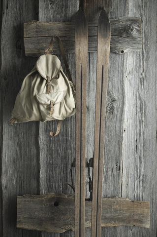 Holzski und alter Rucksack an einer rustikalen Holzwand, lizenzfreies Stockfoto