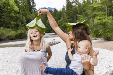 Mutter mit zwei Kindern spielt mit Blättern am Flussufer - TCF05769