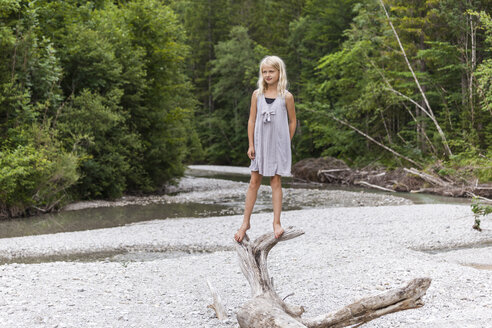 Mädchen steht auf Totholz am Flussufer - TCF05774