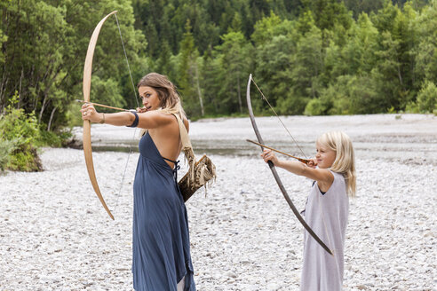Mutter und Tochter beim Zielen mit Pfeil und Bogen in der Natur - TCF05787