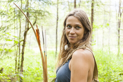 Porträt einer lächelnden Bogenschützin in einem Wald - TCF05792