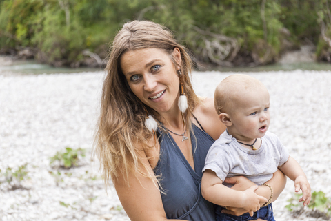 Portrait of smiling mother holding baby boy outdoors in nature stock photo