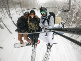 Italy, Modena, Cimone, portrait of happy friends taking a selfie in a ski lift - JPIF00003