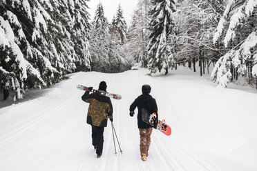 Italien, Modena, Cimone, Rückansicht eines Paares mit Skifahrern und Snowboard im Winterwald - JPIF00011