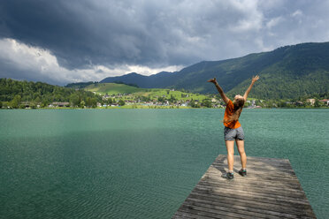 Teenager standing on wooden jetty, raised arms - LBF02024