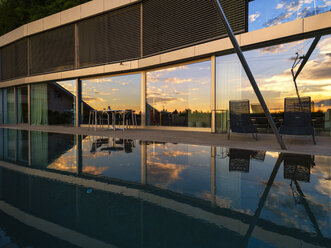 Switzerland, glass front of modern villa at dusk with terrace and pool in the foreground - LAF02075