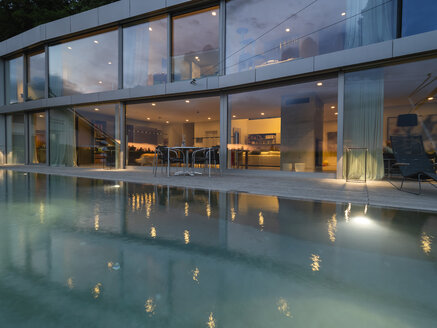 Switzerland, lighted modern villa at dusk with pool in the foreground - LAF02078