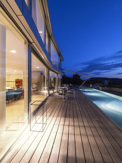 Schweiz, Glasfront, Terrasse und Pool einer beleuchteten modernen Villa in der Abenddämmerung - LAF02087