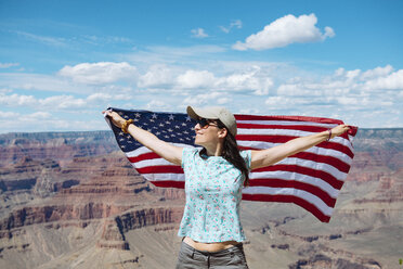 USA, Arizona, lächelnde Frau mit amerikanischer Flagge im Grand Canyon National Park - GEMF02357