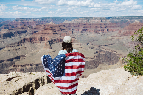 USA, Arizona, lächelnde Frau mit amerikanischer Flagge im Grand Canyon National Park, Rückansicht, lizenzfreies Stockfoto