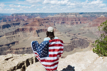 USA, Arizona, lächelnde Frau mit amerikanischer Flagge im Grand Canyon National Park, Rückansicht - GEMF02366