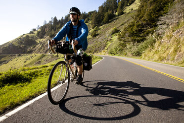 Ein männlicher Radfahrer fährt mit seinem Tourenrad auf dem Pacific Coast Highway in der Nähe von Jenner, Kalifornien. - AURF01973
