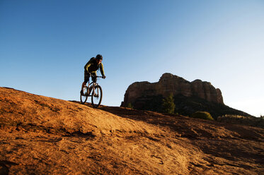 Ein Mann mittleren Alters fährt mit seinem Mountainbike durch die rote Felslandschaft von Sedona, AZ. - AURF01994