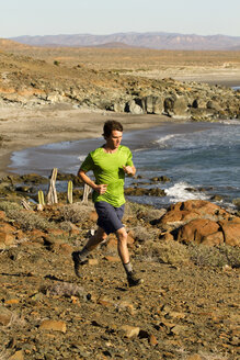 Ein Mann in grünem Hemd läuft entlang der Küste in Zentral-Baja, Mexiko. - AURF01996
