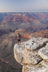 Ein Mann steht auf einem Felsvorsprung und betrachtet die Aussicht auf eine Wüstenschlucht. - AURF02003