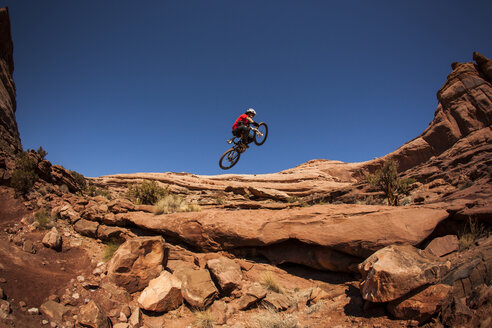 Ein Mann holt bei einem Sprung mit seinem Mountainbike in der Nähe von Moab, Utah, Luft. - AURF02004