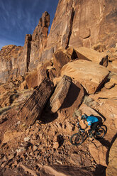 Ein Mountainbiker fährt auf einer technischen Strecke in einer felsigen Wüstenlandschaft. - AURF02009