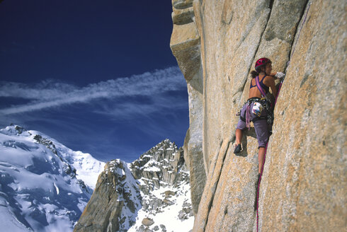 Eine starke Bergsteigerin nimmt eine Felswand hoch oben auf der Auiguille Di Midi in Angriff. - AURF02089