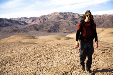 Ein junger Mann wandert mit dem Rucksack durch die Confidence Hills im Death Valley Nation Park, Kalifornien. - AURF02107