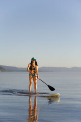 Eine Frau, Stand Up Paddleboarding (SUP) auf dem Lake Tahoe in den frühen Morgenstunden auf ruhigem, glasigem Wasser, CA. - AURF02114
