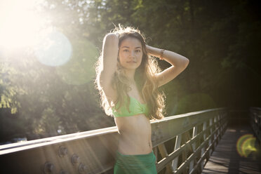 Eine junge asiatische Frau im Bikini entspannt sich an einem heißen Tag auf einer Brücke. - AURF02115