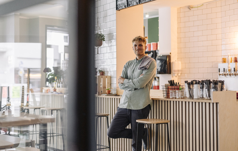 Young man working in his start-up cafe, portrait stock photo