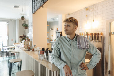 Junger Mann arbeitet in seinem Start-up-Café, steht an der Bar und träumt - GUSF01236