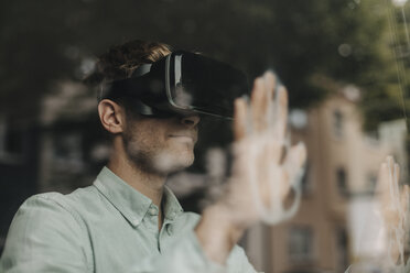 Young man standing at the window, using VR glasses - GUSF01258