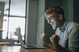 Young man using laptop, laughing happly - GUSF01278