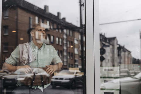 Young business owner sitting in his coffee shop, daydreaming stock photo