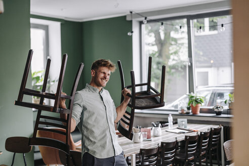 Young business owner lifting chairs - GUSF01287