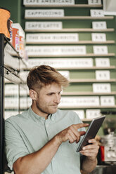 Junger Geschäftsinhaber verwendet digitales Tablet in seinem Café - GUSF01289