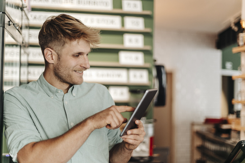 Young business owner using digital tablet in his coffee shop stock photo