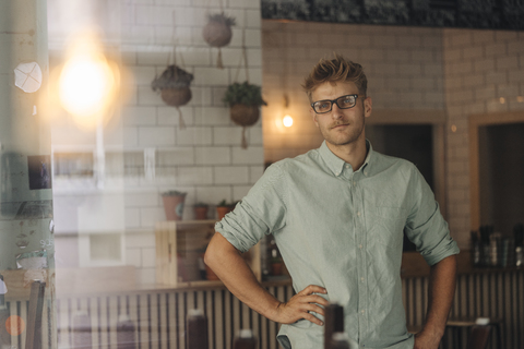 Young business owner standing in his coffee shop stock photo