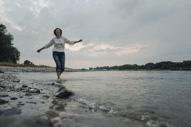 Lachende Frau beim Laufen am Flussufer - KNSF04349