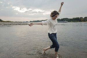 Lachende Frau beim Laufen am Flussufer - KNSF04350