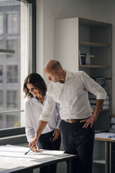 Two architects working in office, discussing blueprints - KNSF04372