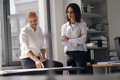 Zwei Architekten arbeiten in einem Büro und besprechen Entwürfe, lizenzfreies Stockfoto