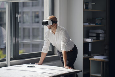 Businessman standing in his office, using VR glasses - KNSF04381