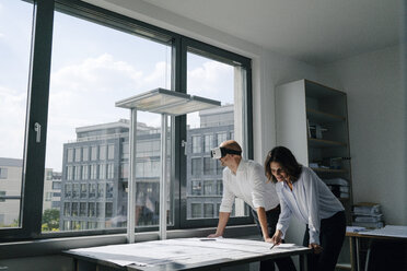 Two architects working on blueprints, man using VR glasses - KNSF04382