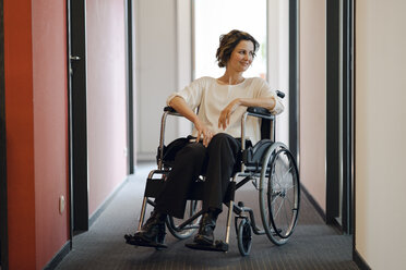 Disabled business woman sitting in wheelchair, with laptop on knees - KNSF04396