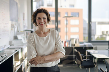 Successful businesswoman standing in her office with arms crossed - KNSF04399